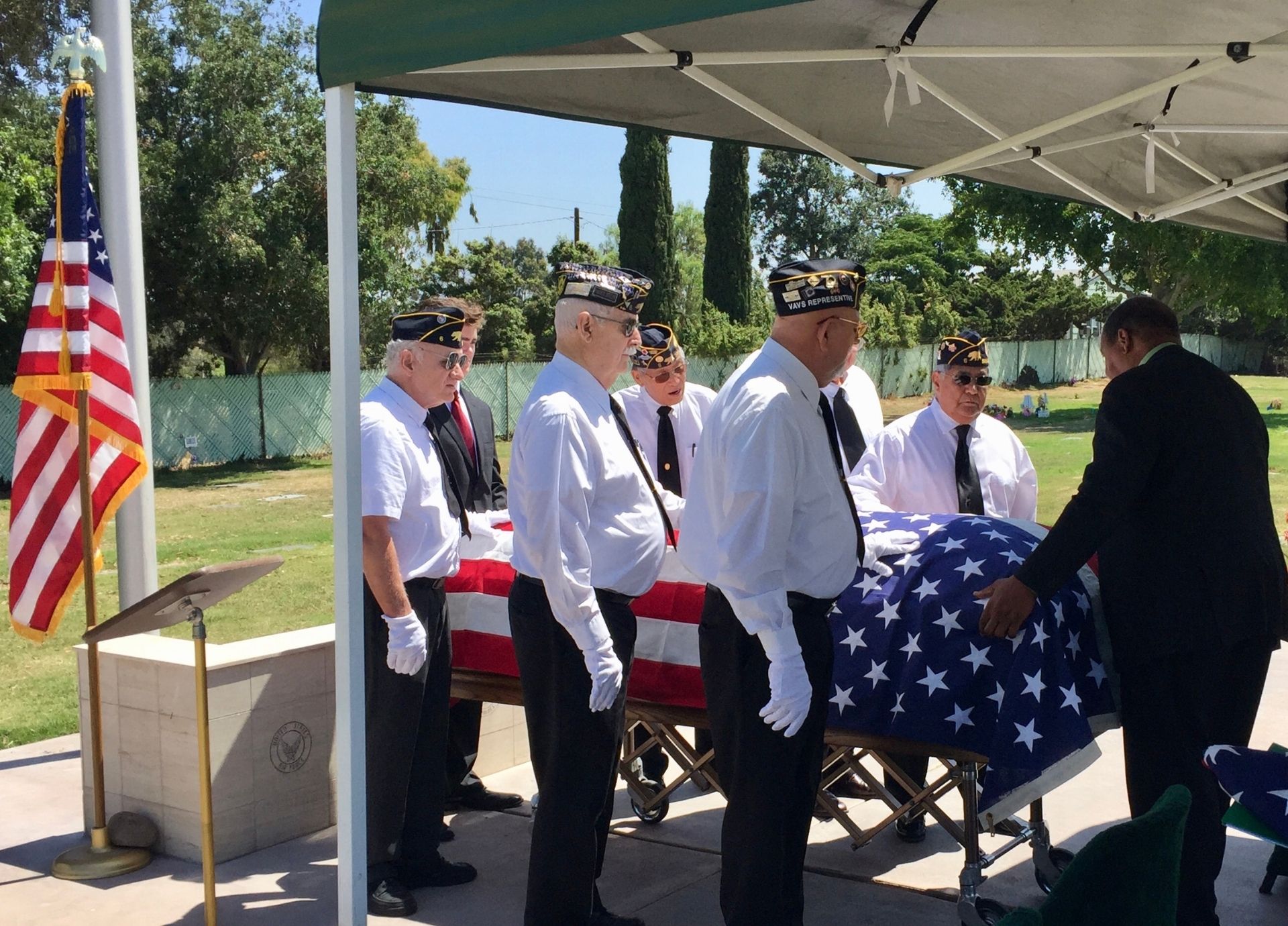 American Legion Post 6 honor guard performing military funeral service with flag-draped casket