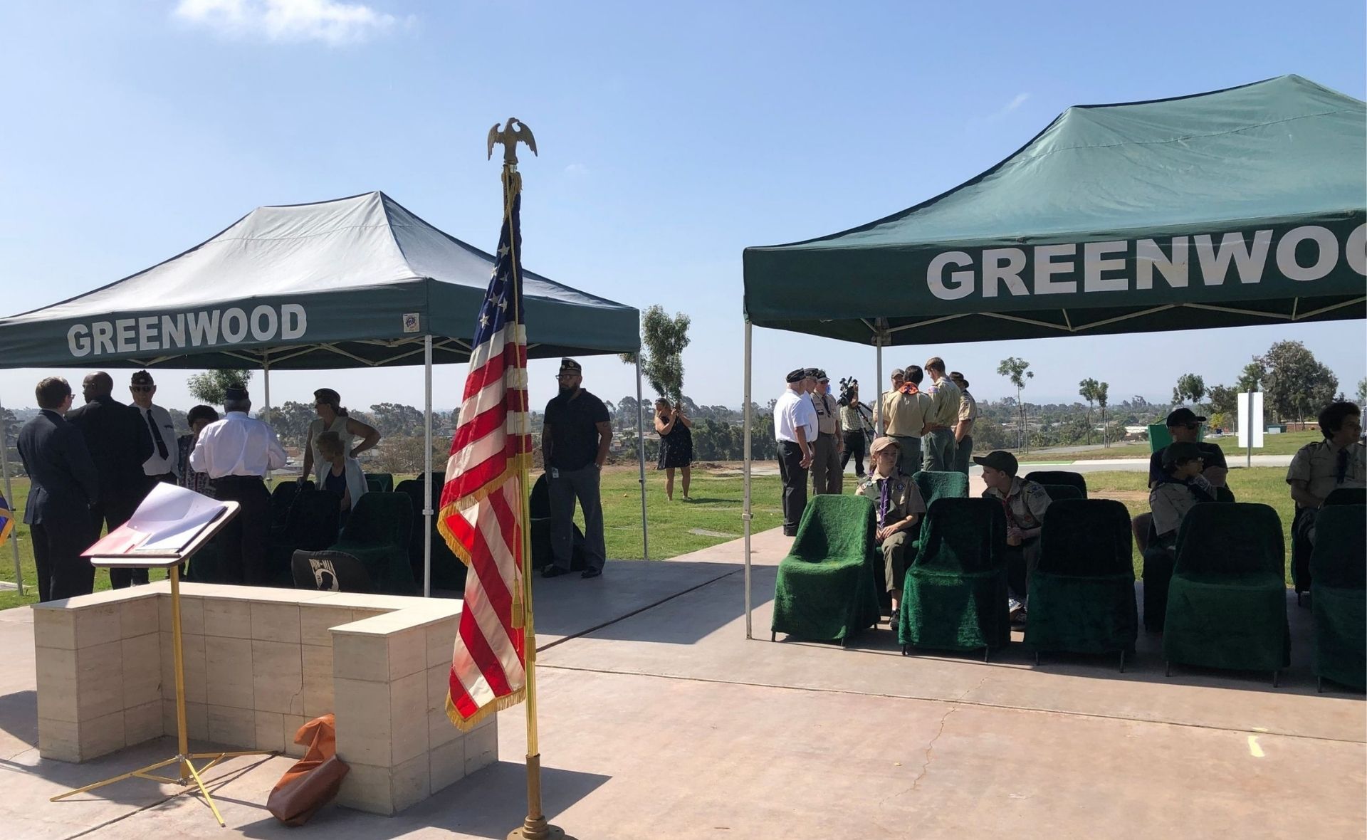 Military funeral service at Greenwood Memorial Park with American flag and formal ceremony setup