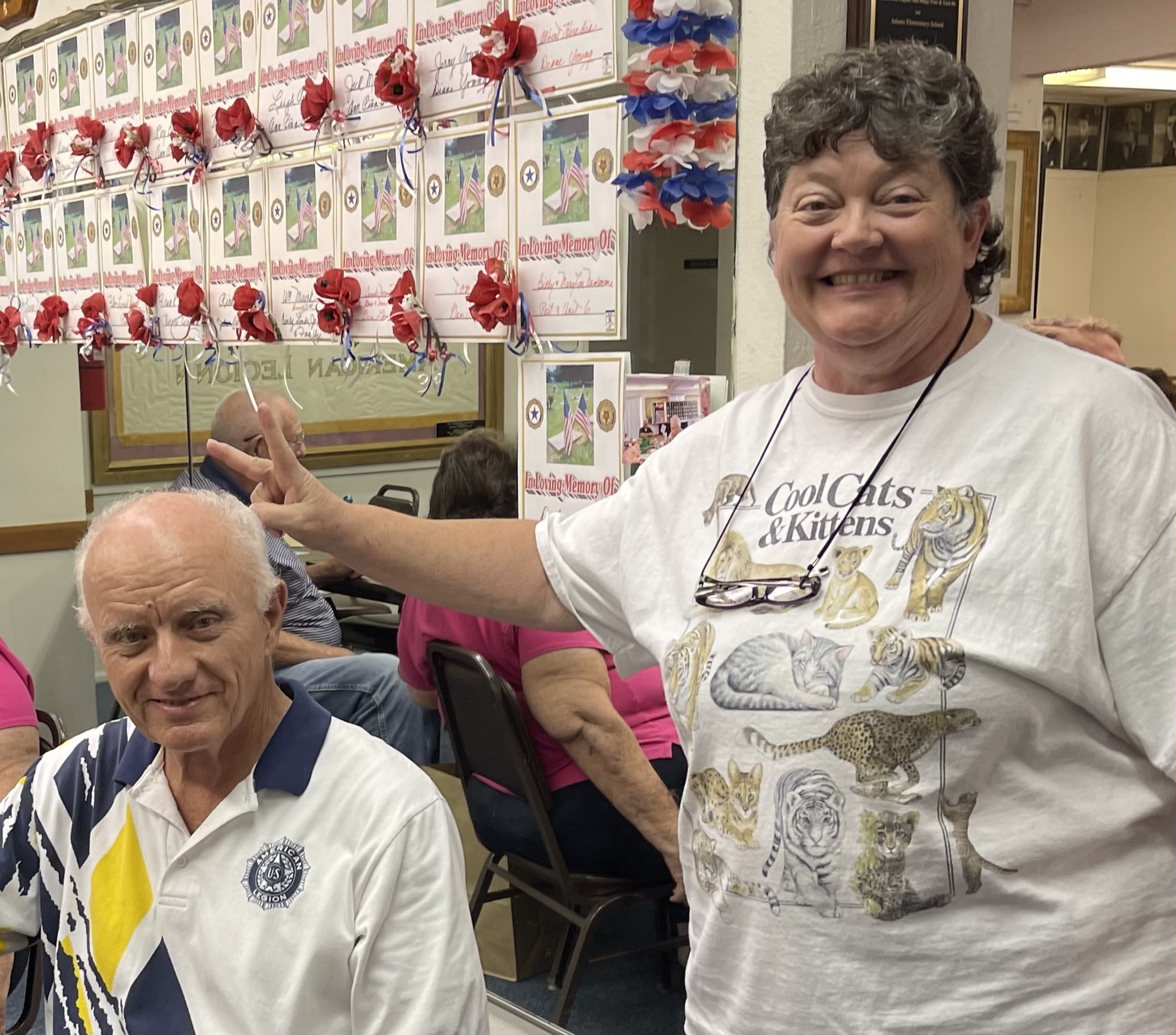 Smiling participants at American Legion Post 6 bingo night with memorial wall in background